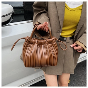 Detail of a brown bucket bag with accordion pleats and soft drawstring side accents