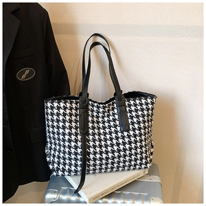 Chic houndstooth tote bag detail styled on a silver suitcase for urban fashion look
