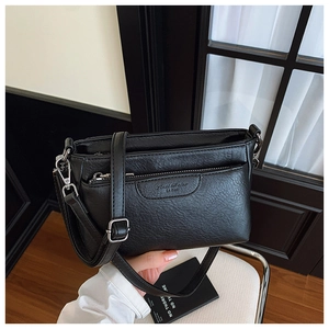 Detail of black crossbody bag featuring pebbled leather texture and silver hardware