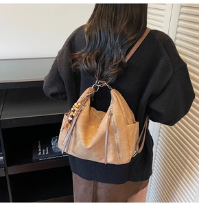 Detail of light brown matte leather backpack with silver zippers and beaded charm detail