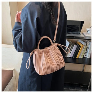 Detail of a dusty pink pleated leather bucket bag shown in a stylish office lifestyle setting