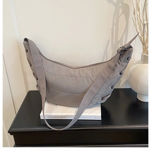 Detail of grey quilted dumpling bag showing crescent shape and side drawstring texture