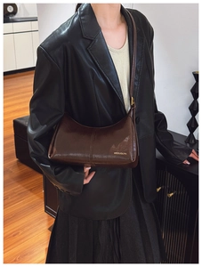 Detailed view of dark brown leather crossbody bag texture and metallic brand logo