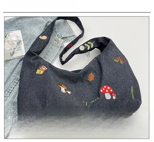 Détails de broderie de champignons et hérisson sur sac cabas en denim bleu avec zip