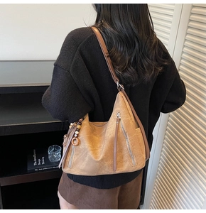 Rear view of model wearing brown leather tote bag with vintage tassel and silver zippers