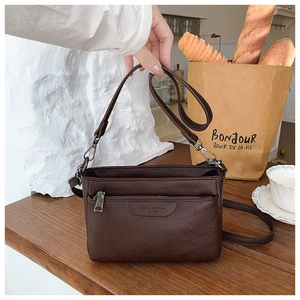 Detailed view of dark brown PU leather crossbody bag with silver buckle and front zipper