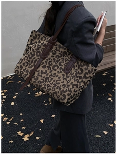 Large leopard print tote bag with brown leather handles shown worn over the shoulder