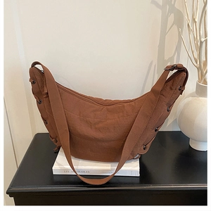 Detail of dark brown crescent bag with drawstring eyelets on textured nylon fabric