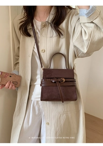 Detalle del bolso de ante marrón oscuro con hebilla dorada y estilo retro minimalista