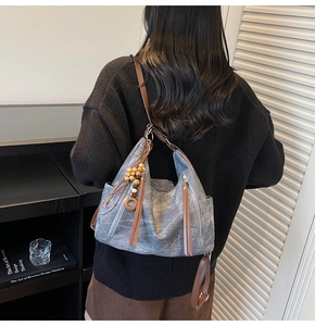Detail of grey canvas tote bag with brown leather straps and wooden bead fringe charm