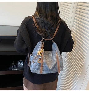 Detail of washed leather backpack in grey-blue with brown straps and bead charms