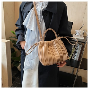 Detail of khaki pleated bucket bag with adjustable strap in a stylish minimalist setting