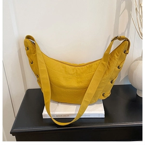 Detail of a bright yellow crescent bag with textured fabric and drawstring accents
