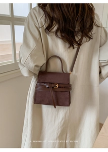 Bolso bandolera chic de ante marrón oscuro con un abrigo beige en ambiente elegante