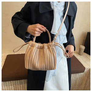 Detail of pleated bucket bag in beige faux leather with top handle and shoulder strap