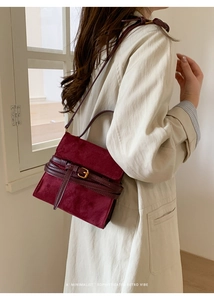 Detalle de bolso de ante sintético burdeos con hebilla decorativa y herrajes dorados en una modelo