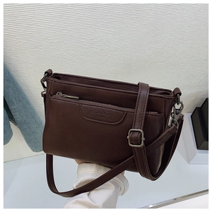 Detail of dark brown leather crossbody bag with metal zipper and embossed branding