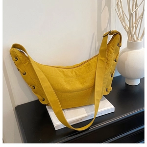 Close-up of a yellow crescent hobo bag with eyelet details and wrinkled fabric texture