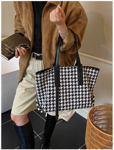 Detailed view of houndstooth tote bag with black leather straps and spacious interior