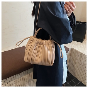 Detailed view of beige ruched bucket bag with fine leather texture and handle design