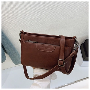 Detailed view of dark brown leather crossbody bag with front zipper and embossed logo
