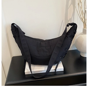 Detail shot of black nylon hobo bag featuring side metal eyelets and drawstring accents