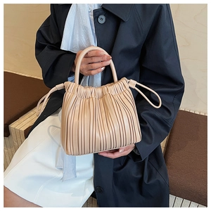 Close-up of pleated beige bucket bag showing vertical folds and drawstring closure detail