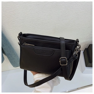 Detail view of black PU leather shoulder bag with zipper pocket and silver buckle strap
