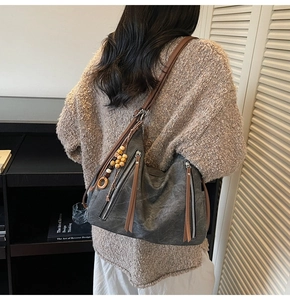 Detail of dark grey retro shoulder bag with brown tassels and wooden bead charm