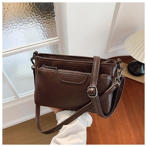 Macro detail of deep brown matte PU leather shoulder bag with logo and zipper pocket
