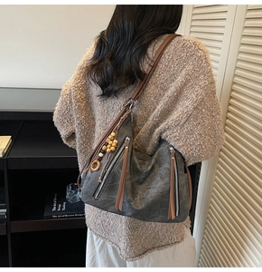 Detail of grey hobo bag showing wooden beads, fringes, and brown leather straps