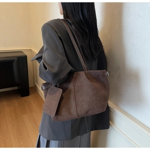 Detailed side view of a brown suede tote bag with a small matching coin purse and buckle