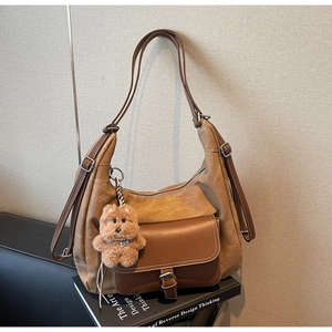 Dettaglio borsa hobo in patchwork marrone a contrasto con ciondolo cane e fibbie argento