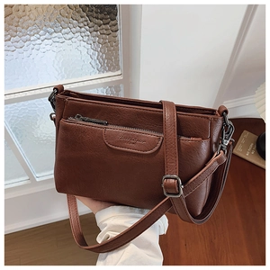 Close-up of vintage brown leather crossbody bag featuring a front pocket and metallic hardware