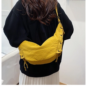 Detail of yellow crescent shoulder bag featuring side grommets and drawstring texture