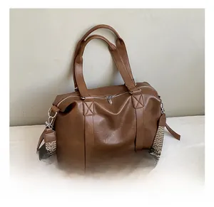Detail of a brown PU leather boston bag with stylish patterned wide shoulder strap