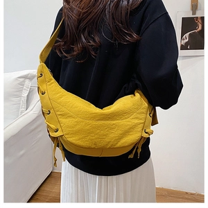 Detail of yellow crescent shoulder bag with knot ties and metallic eyelet accents