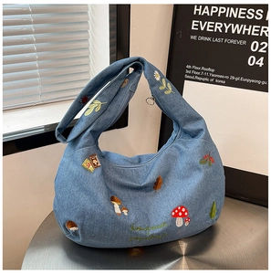 Détail du sac hobo en denim avec broderies de nature et inscription bonjour brodée