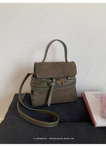 Detalle del bolso bandolera de ante gris oscuro con correas de cuero verde oliva y hebillas