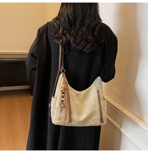 Detail of off-white textured hobo bag with ethnic tassel and brown double straps