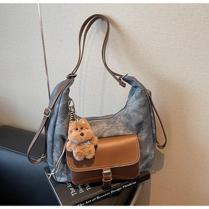 Dettaglio della borsa hobo in denim vintage con tasca in pelle e ciondolo orsetto peluche