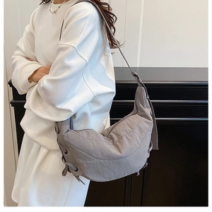 Detail of grey dumpling bag showing pleated nylon texture and adjustable side drawstrings