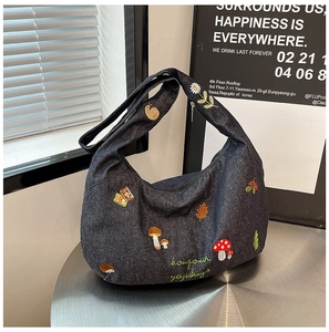 Détails de broderies forestières sur un sac besace en denim gris foncé en forme de lune