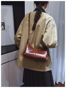 Detail of vintage brown glossy patent leather shoulder bag with gold brand logo