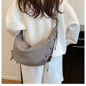 Detail view of grey nylon crescent bag featuring adjustable drawstring side knot