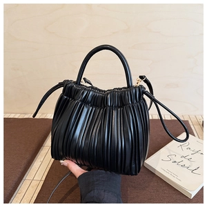 Close-up detail of black pleated PU leather bucket bag with top handle and strap