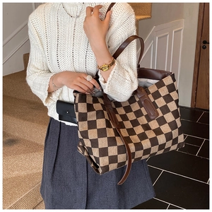 Detail of checkered tote bag showing woven texture and dark brown leather shoulder strap