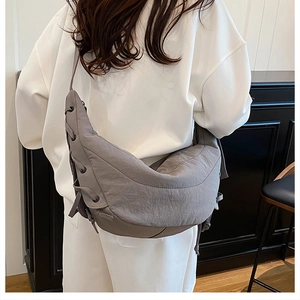 Detailed side view of grey crescent shoulder bag with unique lace-up decorative straps