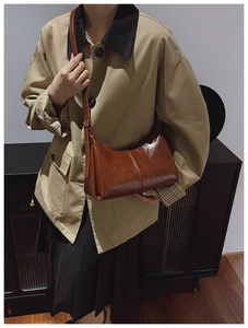 Detail view of dark brown retro shoulder bag with gold logo and stylish vertical stitching