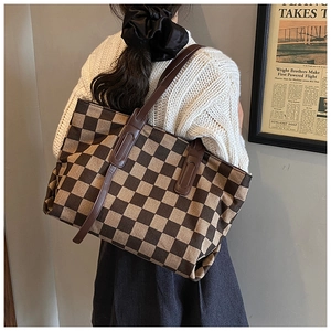 Model view of a brown checkerboard tote bag paired with a white knit sweater